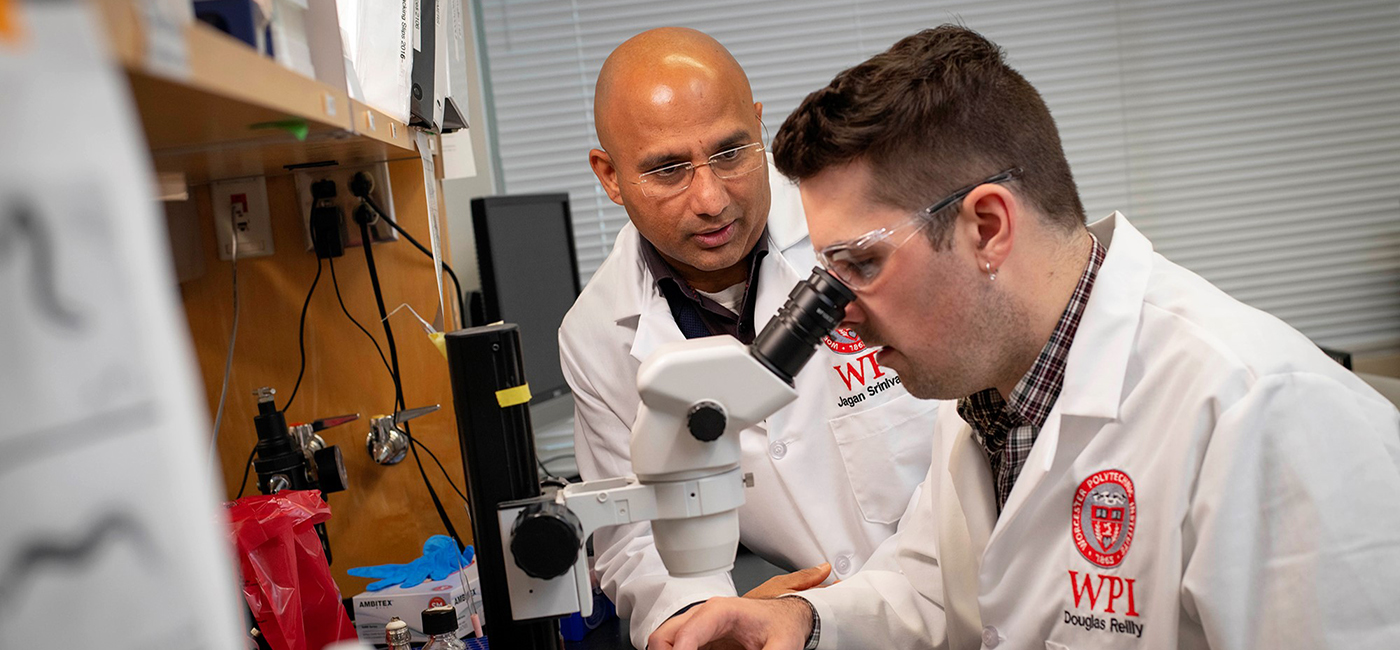 Professor aiding student with microscrope