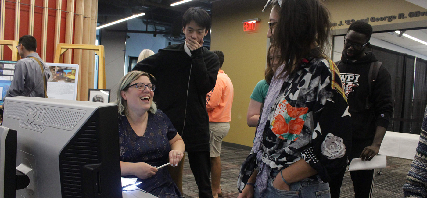 A group of WPI students standing around a computer conversating