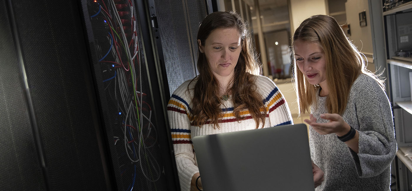Two students configuring server racks with laptop