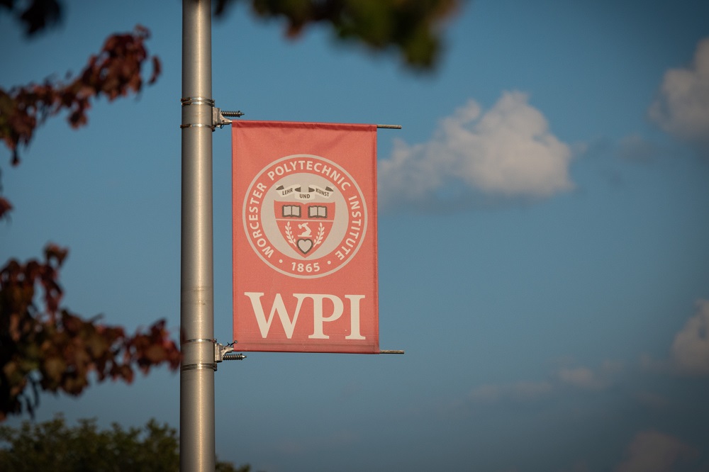 WPI banner hanging on pole with blue sky in background