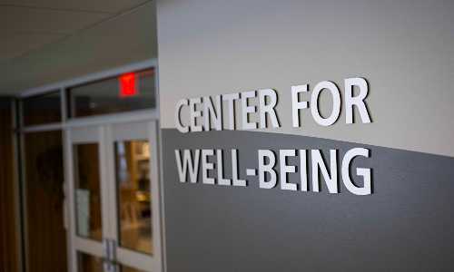 The Center for Well-Being sign in gray typography on a light gray wall.