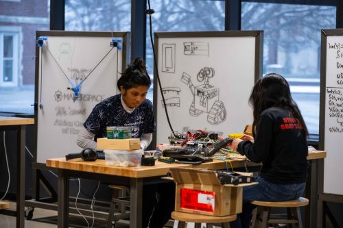 two students with assortment of tech materials working together