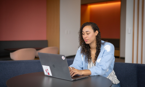 A lady at a table, working on her laptop