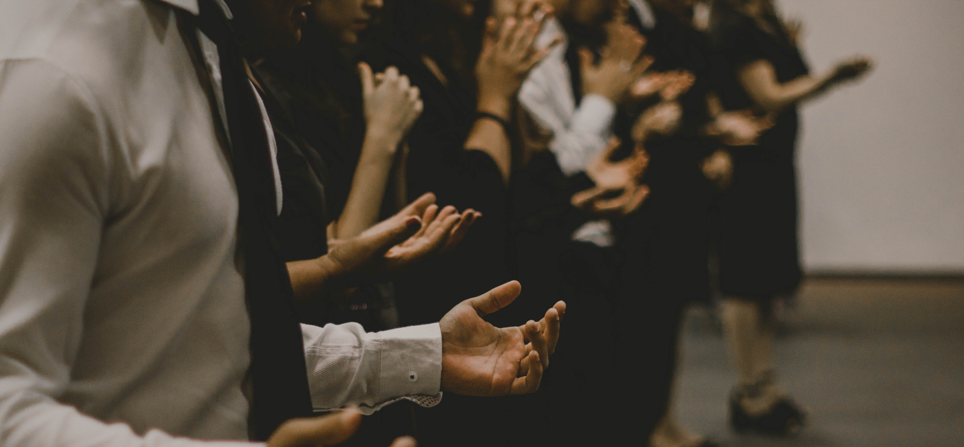 A line of people with their hands out, worshipping.