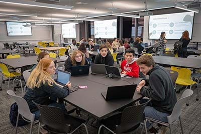 Students gather at tables for subcommittee discussions during a Green Team meeting.