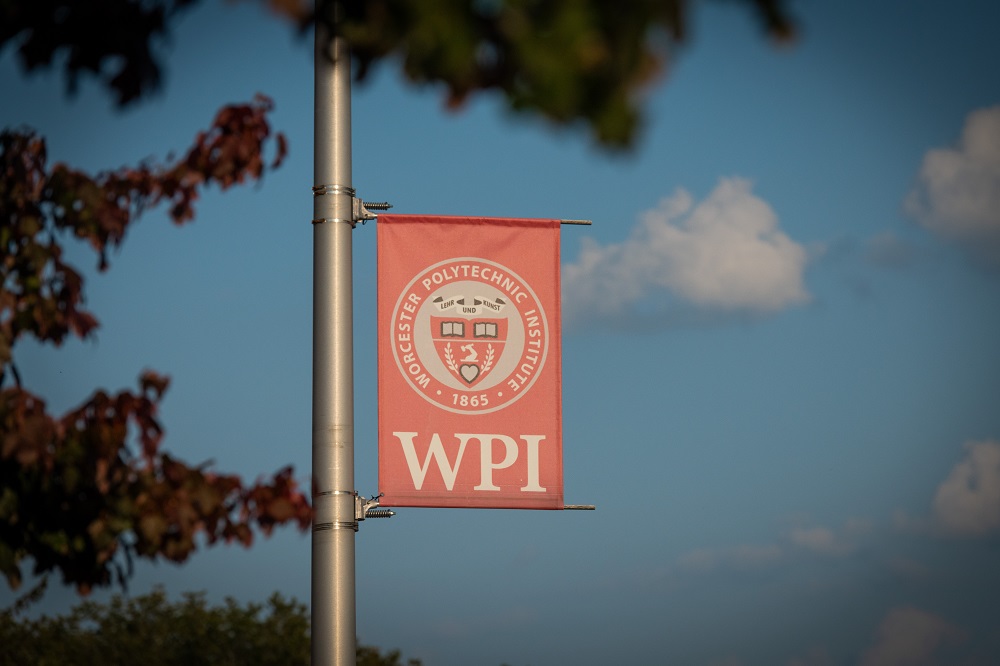 WPI banner hanging on pole with blue sky in background