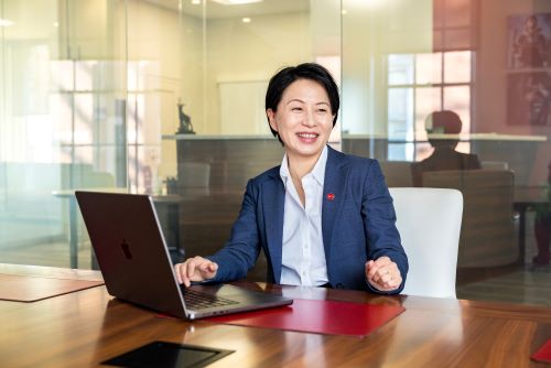 Grace Wang sitting at a table with an open laptop in front of her, slightly to the side