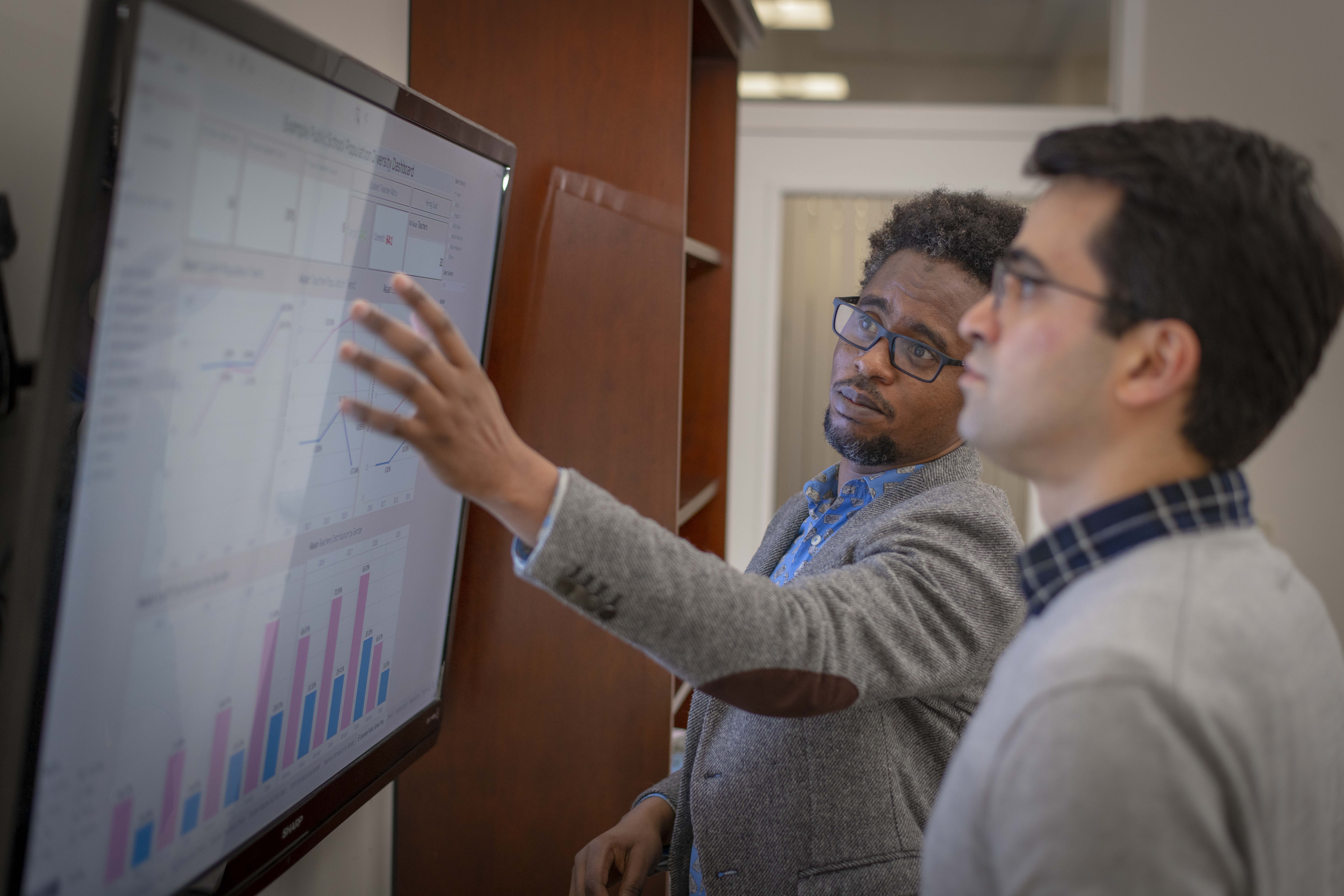 Professor points to data points on screen with a student