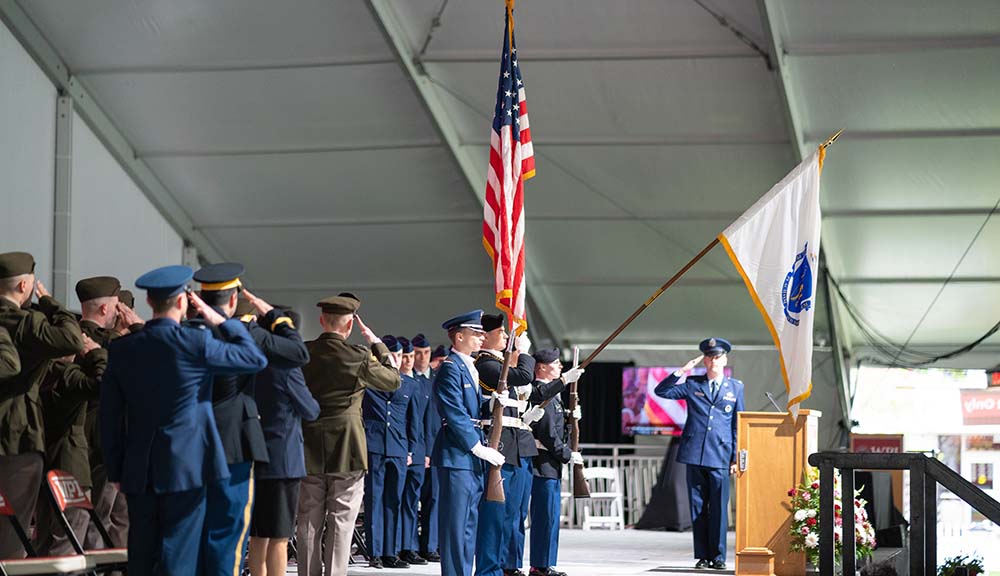 Attendees and cadets salute the American flag during the ROTC commissioning ceremony.