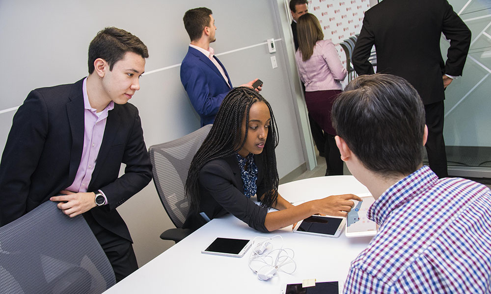 Group of students gather around a financial app on a cell phone