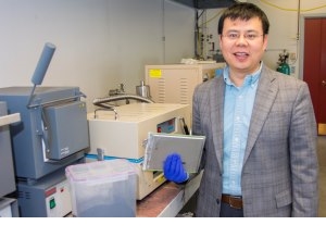 Yan Wang holds a lithium-ion battery cell used in electric vehicles. His process breaks down the batteries to produce the powder shown to the left. New cathode materials can be made from this powder.