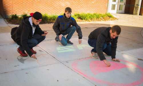 Students drawing chalk art on the sidewalk outside the campus center