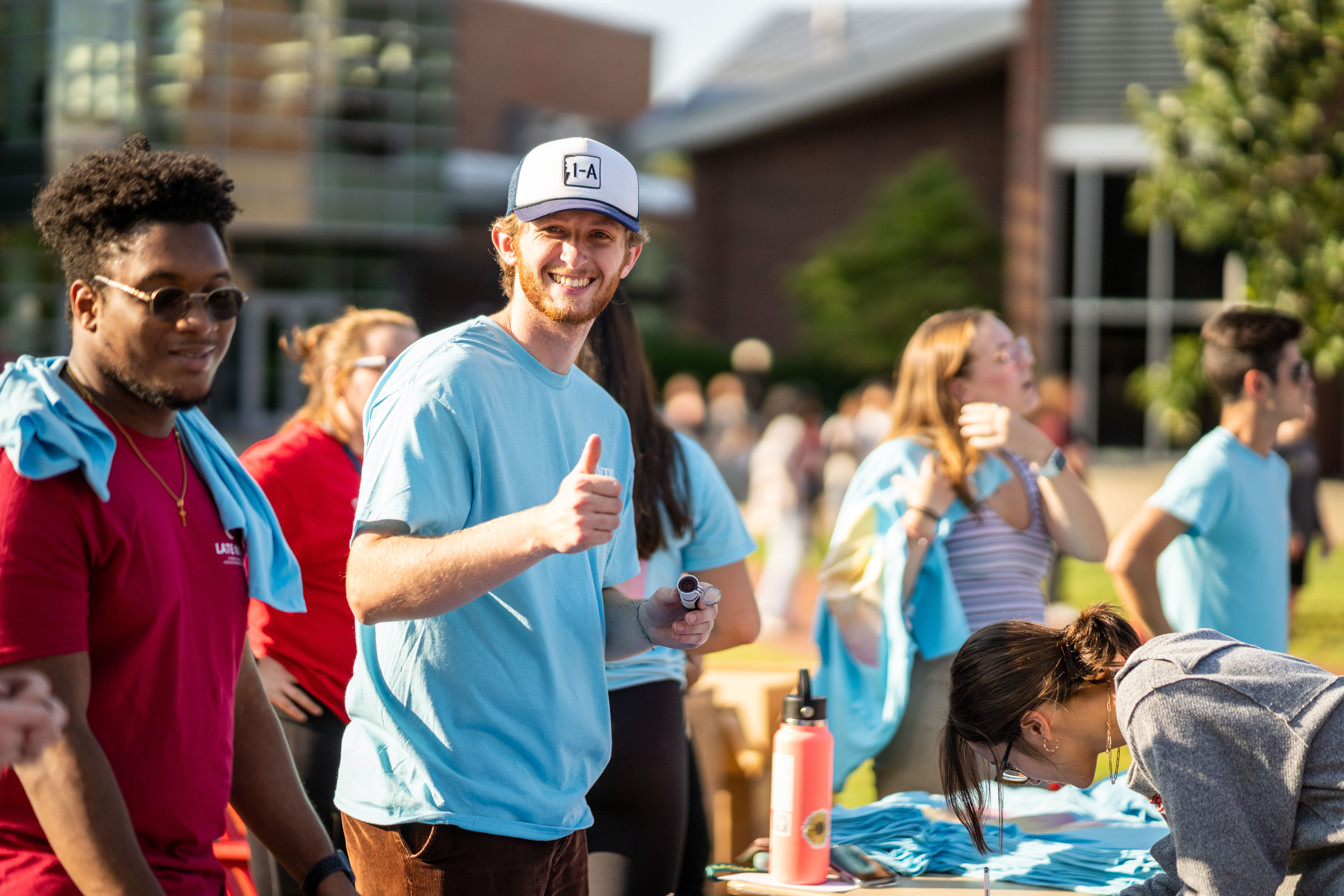 A student gives a thumbs-up to the camera on the Quad.