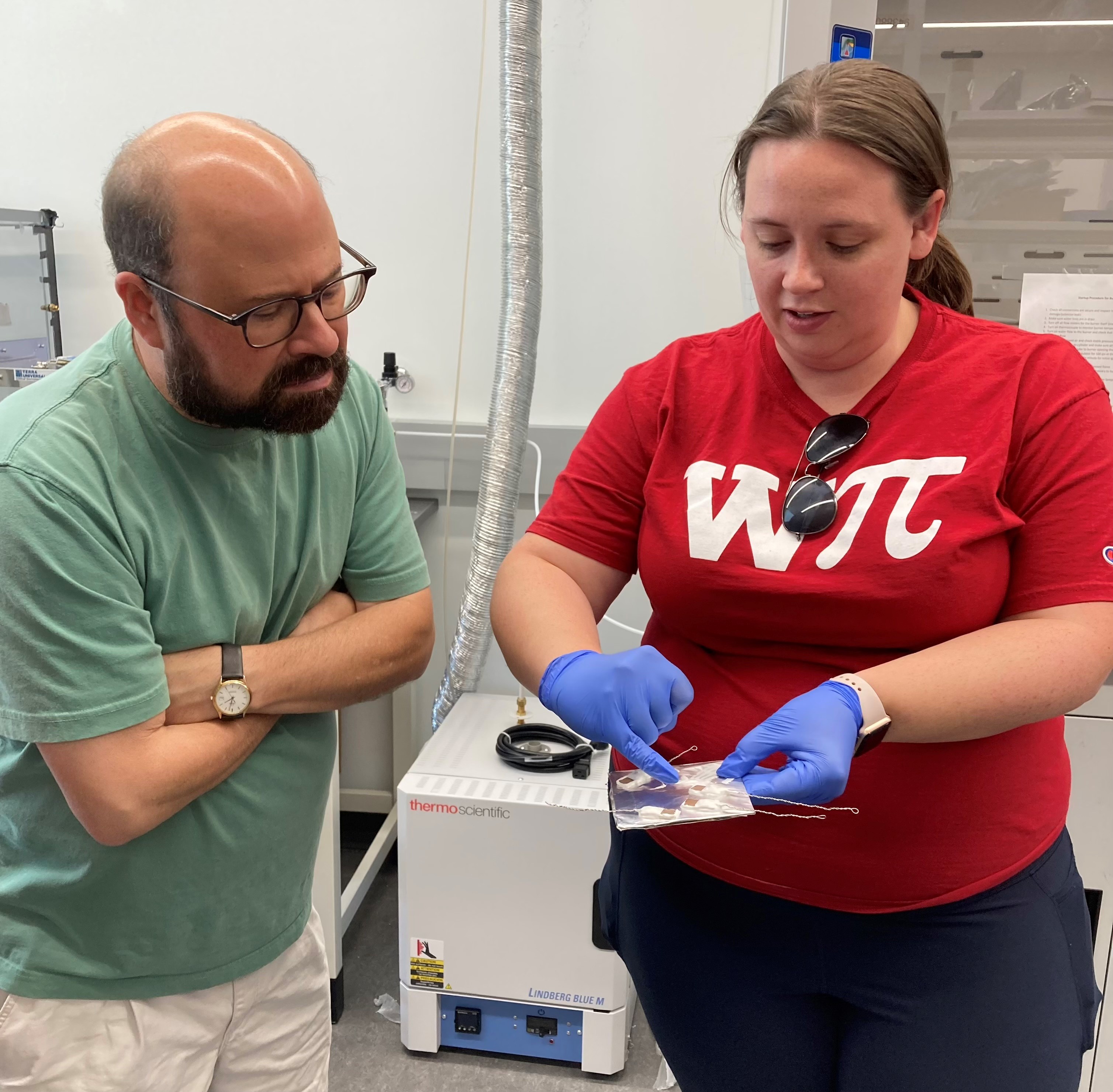 One teacher pointing to an electronic plate while another looks on