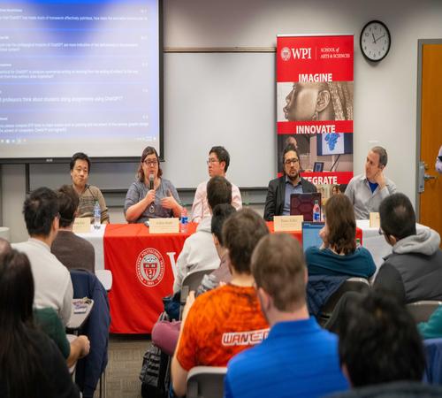 a group of people speaking at a panel behind a table