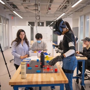 three students working on a project with robotic vehicle on table top