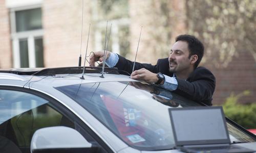 WPI’s Alex Wyglinski affixes an antenna on the roof of a car.