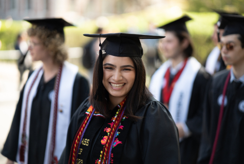 Graduate smiling at camera with cap and gown