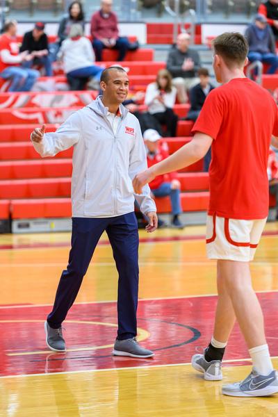 David Brown high-fiving a basketball player on the court