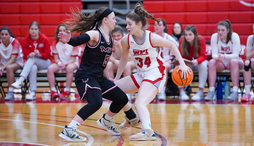 A member of the women’s basketball team dribbles around an opponent.