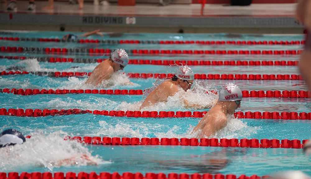 Three members of the swimming and diving team compete in the pool.