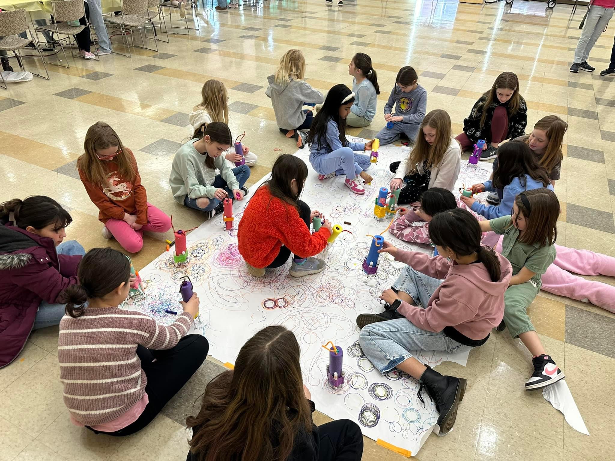 students testing their scribble bots on large sheet of paper
