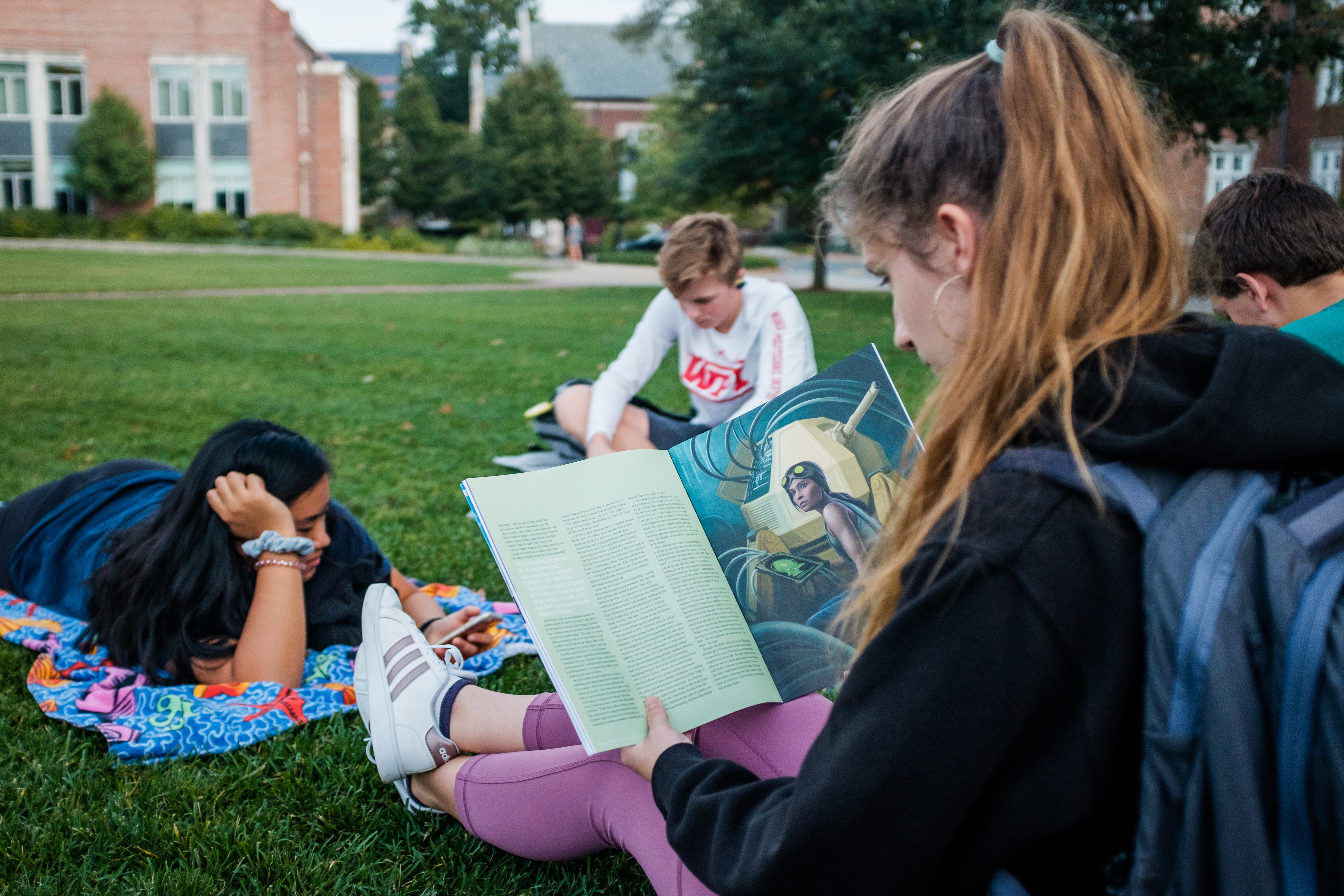student on lawn reading magazine