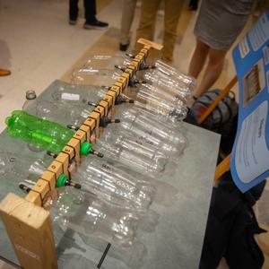 clear plastic bottles with one green plastic bottle on a rack facing each other for SDG work