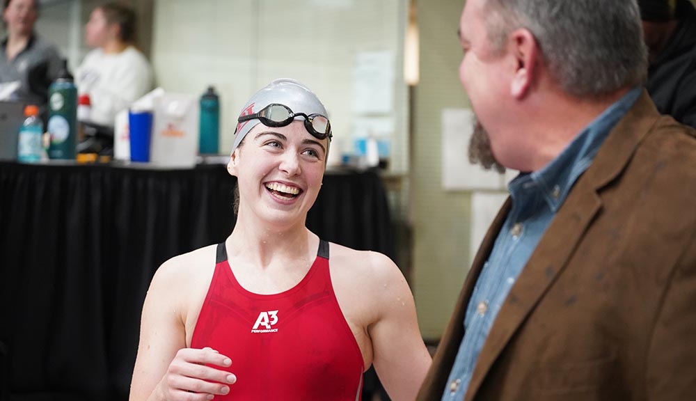 A member of the women’s swim team smiles at her coach after a meet.