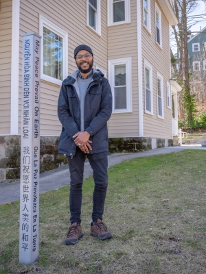 Kalvin Cummings stands next to a peace pole, which can serve as a gathering place for student spirituality groups