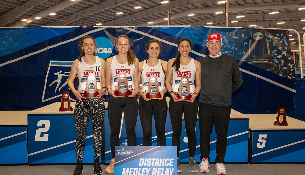 Student athletes smile with their coach during a competition event.