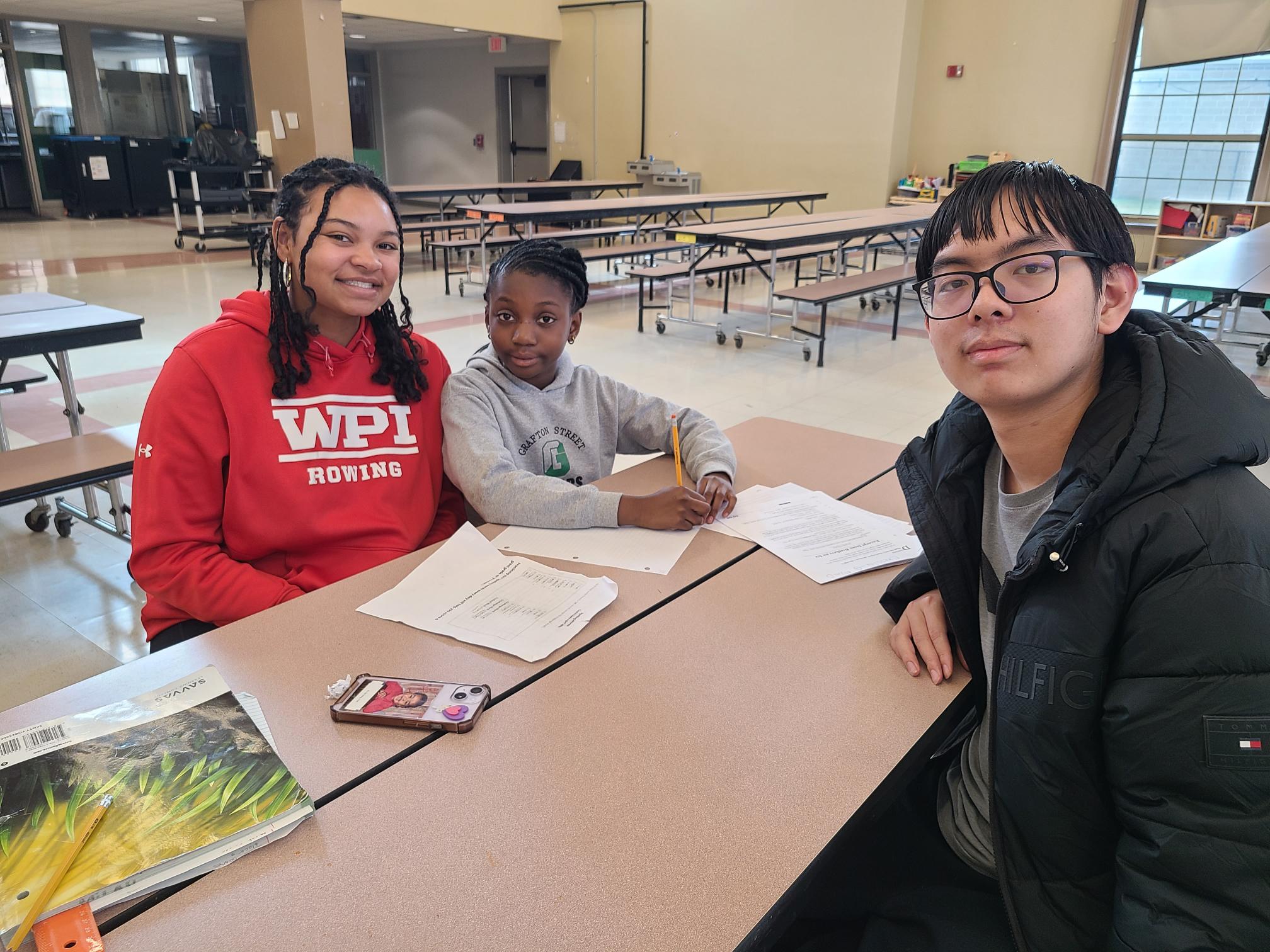 WPI students, Jonell English and Ivan Zheng assist a student with homework.