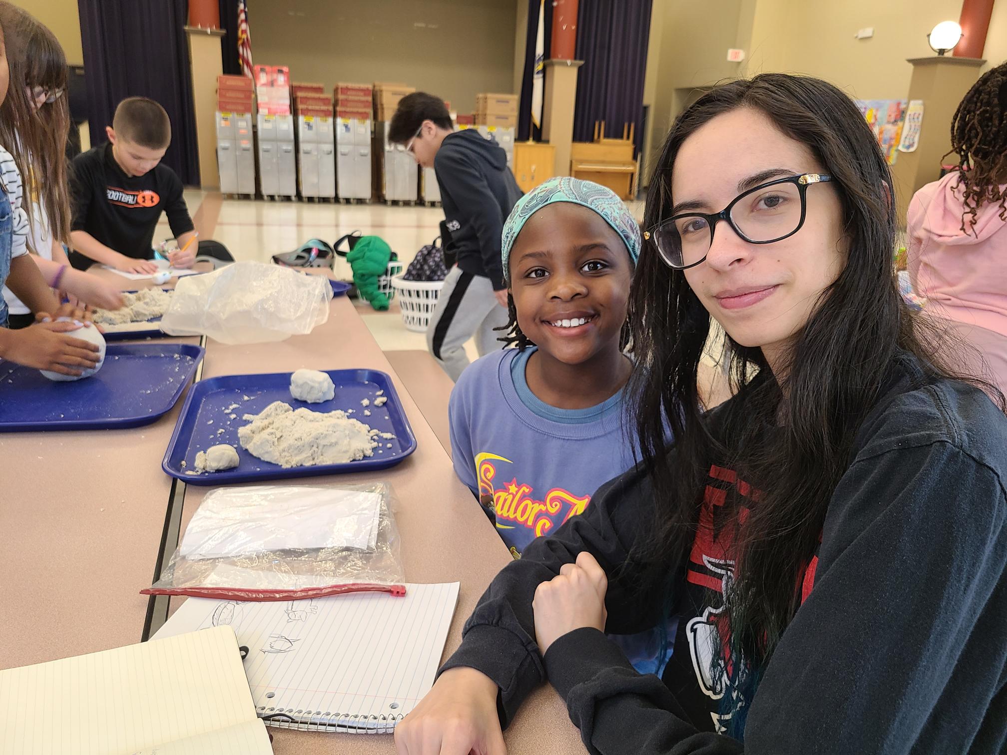 WPI student Rebekah Mendoza assist students with hands-on activity using sand clay.