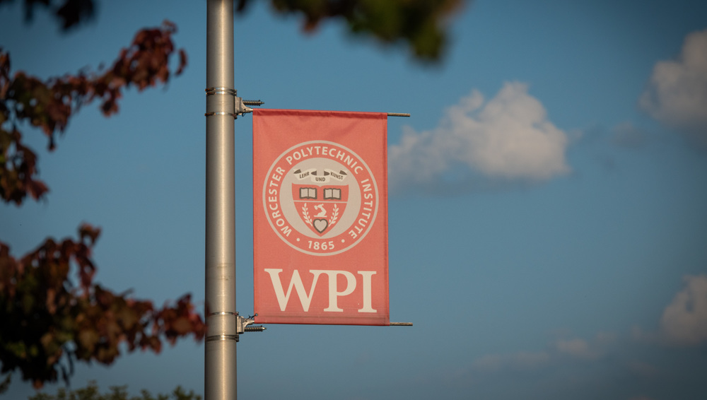 WPI banner hanging on pole with blue sky in background