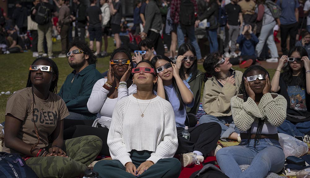 Students wear eclipse glasses while viewing the eclipse.