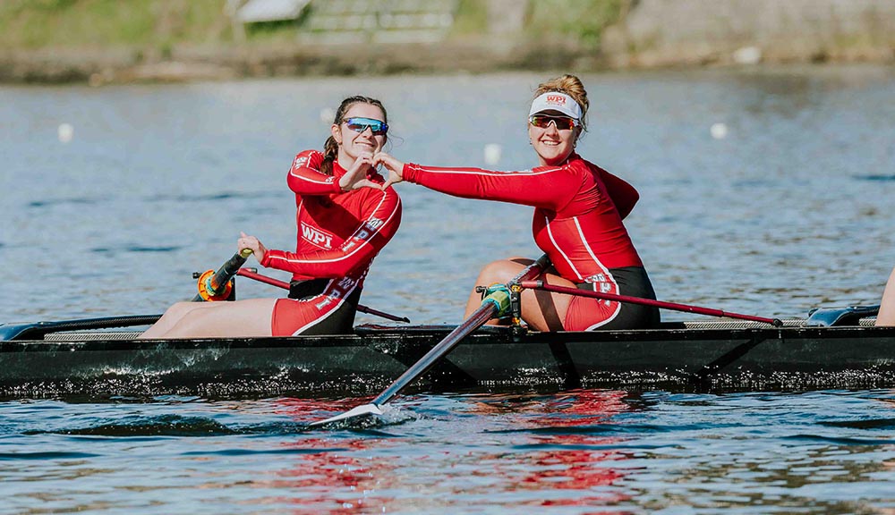 Two members of the women’s rowing team make a heart with their hands.