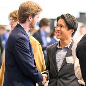 Two people in suits shaking hands at a career fair