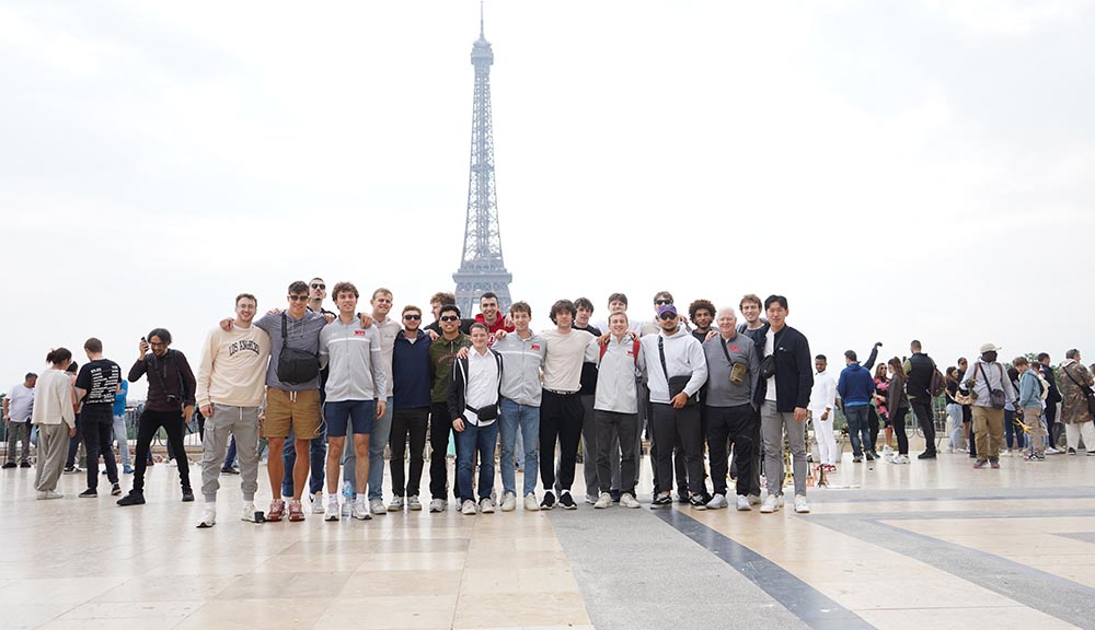 The men’s basketball team poses for a photo in front of the Eiffel Tower.