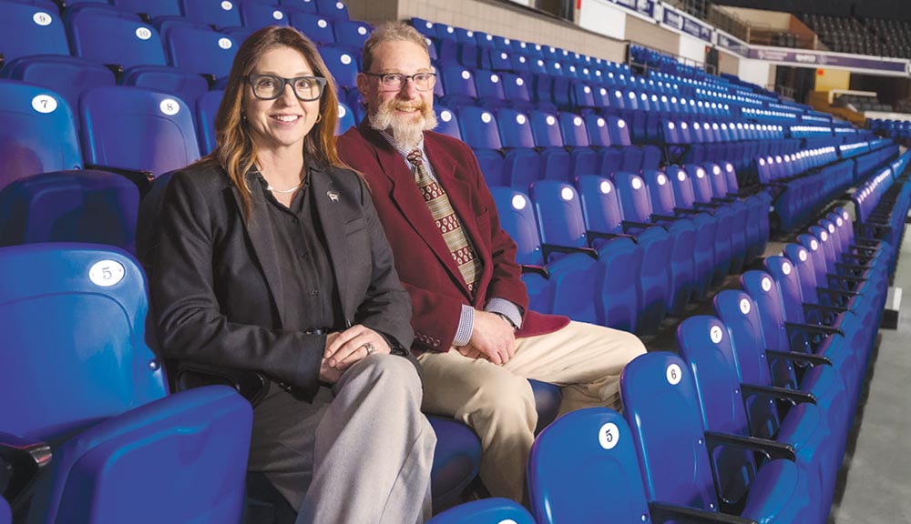 Bill Battelle and Jennifer Parissi-Forti sit together in the stands at the DCU Center.