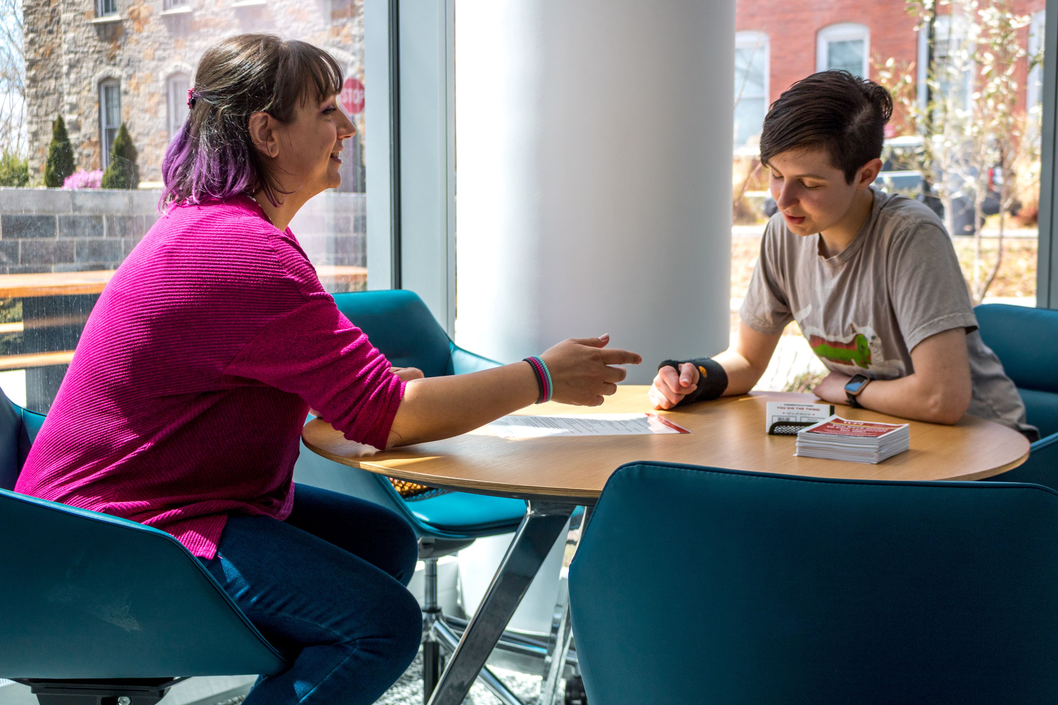 staff and student talking at table