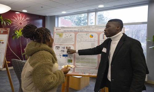 two students discussing a project posterboard