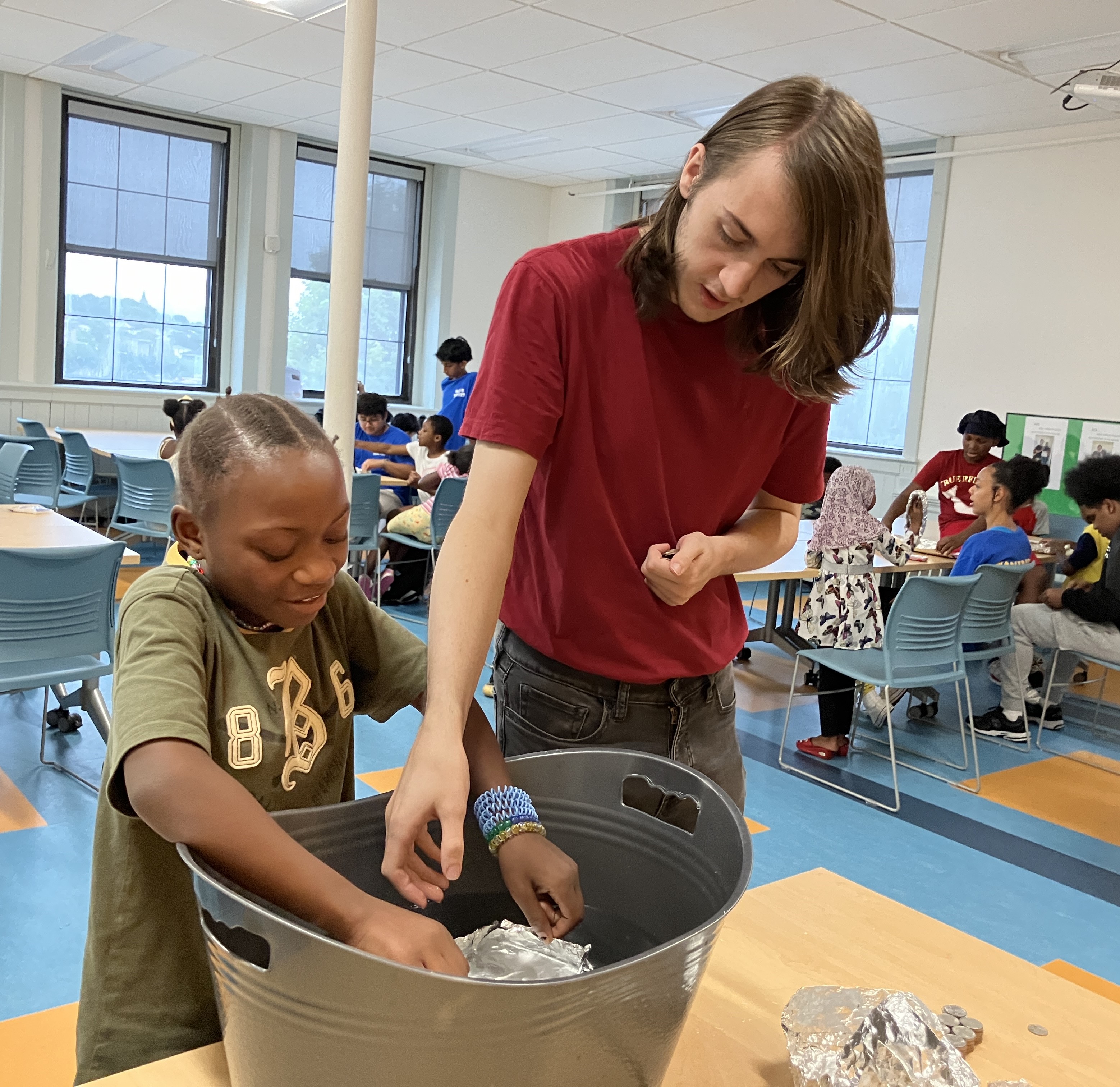 Jake Maglio assisting a student with STEM activity on density and buoyancy.
