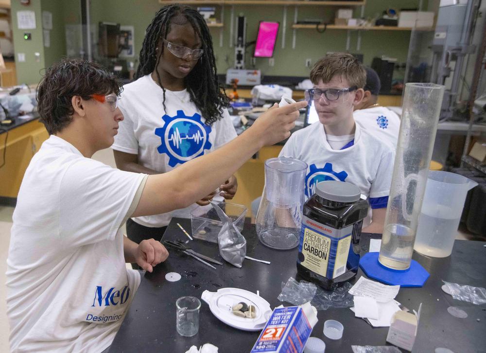 Students work at a laboratory table, examining a water jug