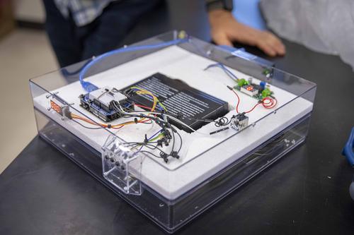 Electronic device sitting on a table, including wires, a box, and a button to operate the device
