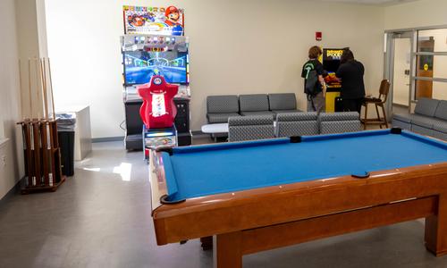pool table in foreground and two students playing a video game in background