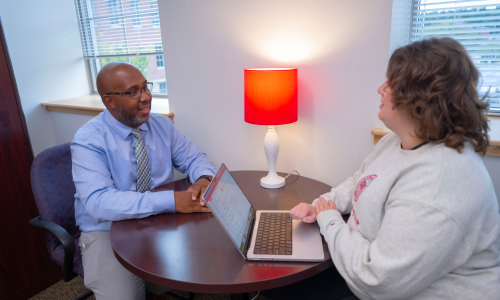 student receiving academic support at small desk with staff