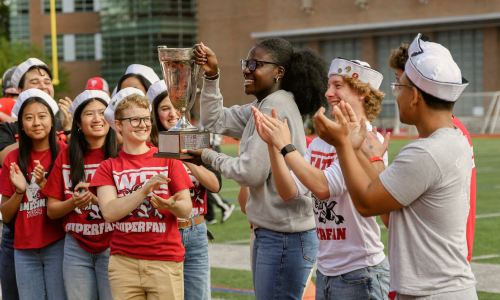 student holding trophy with other prideful wpi students standing around them cheering