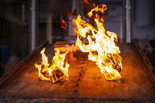 Cardboard models of houses and trees burn on a burn table inside a fire protection engineering laboratory at WPI during an experiment