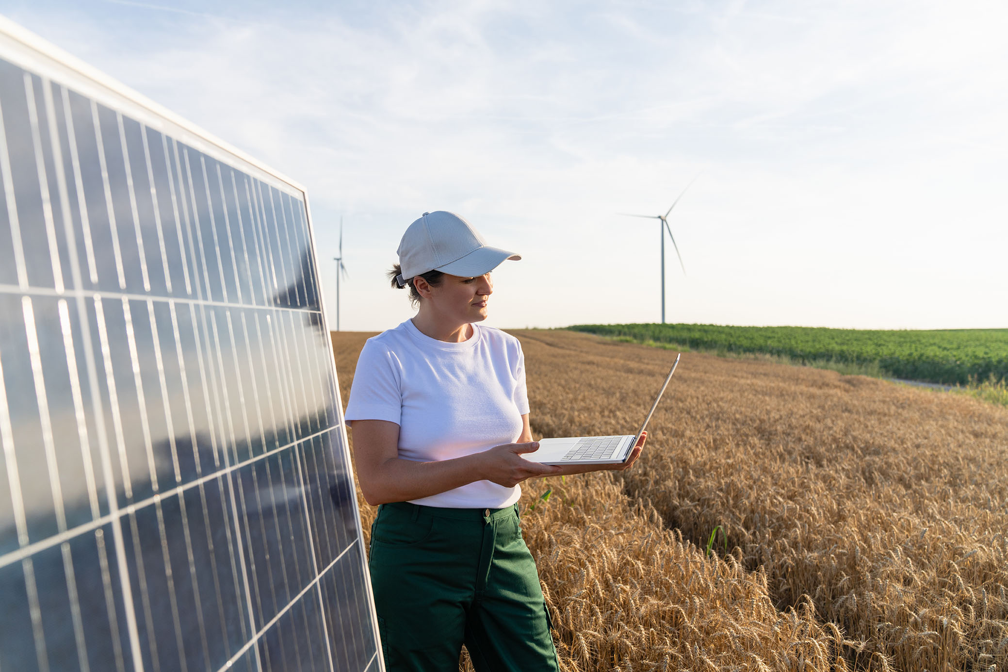 Woman by solar panels in front of windmills.