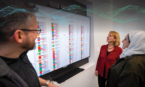 WPI faculty in the AI master’s program stand in front of a screen